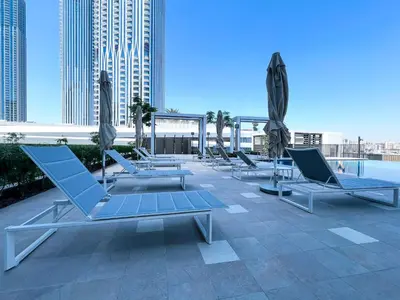 a row of lounge chairs and umbrellas on a roof at Elegant 1 bedroom in Creek Edge in Dubai