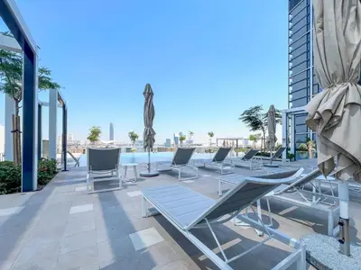 a row of lounge chairs on the roof of a building at Elegant 1 bedroom in Creek Edge in Dubai