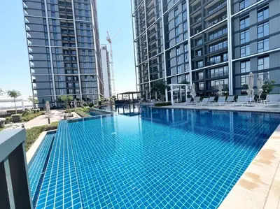 a swimming pool in the middle of two tall buildings at Elegant 1 bedroom in Creek Edge in Dubai