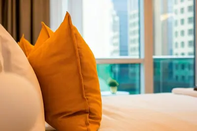an orange pillow sitting on a bed with a window at Spacious Luxe Studio Near Metro in Dubai
