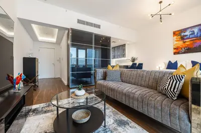 a living room with a couch and a tv at Spacious Luxe Studio Near Metro in Dubai