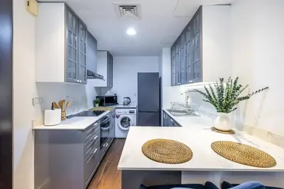 a kitchen with white cabinets and a counter top at Spacious Luxe Studio Near Metro in Dubai