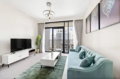 a living room with a blue couch and a tv at Elegant 1 bedroom in Creek Edge in Dubai
