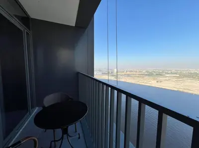 a table and chair on a balcony with a view at Stylish 1 Bedroom High Floor in Creek Edge in Dubai