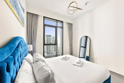 a bedroom with a bed and a large window at Stylish 1 Bedroom High Floor in Creek Edge in Dubai