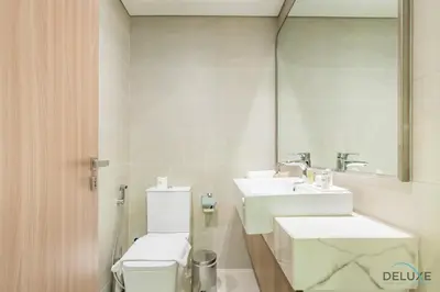 a bathroom with two sinks and a toilet and a mirror at Alluring Studio Apartment at Azizi Riviera 16, Al Merkadh by Deluxe Holiday Homes in Dubai