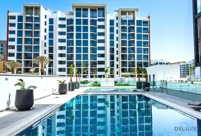 a swimming pool in front of a large building at Alluring Studio Apartment at Azizi Riviera 16, Al Merkadh by Deluxe Holiday Homes in Dubai