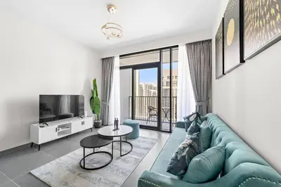 a living room with a blue couch and a tv at Stylish 1 Bedroom High Floor in Creek Edge in Dubai