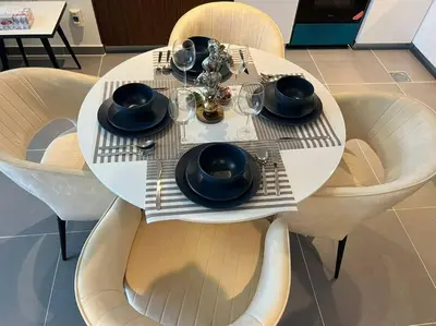 a white table with chairs and a plate of food at Stylish 1 Bedroom High Floor in Creek Edge in Dubai