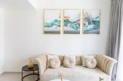 a living room with a couch with three paintings on the wall at Elegant 1 bedroom in Creek Edge in Dubai