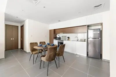 a kitchen with a table and chairs and a refrigerator at Elegant 1 bedroom in Creek Edge in Dubai