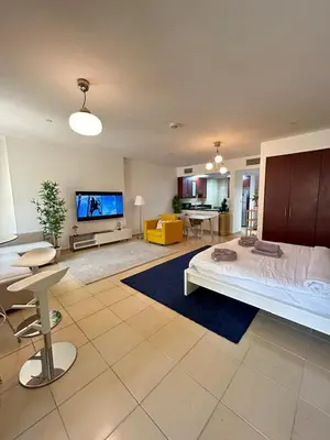 a large living room with a bed and a flat screen tv at Prime Spacious Studio with Vibrant Vibes in JBR By SWEET HOMES in Dubai