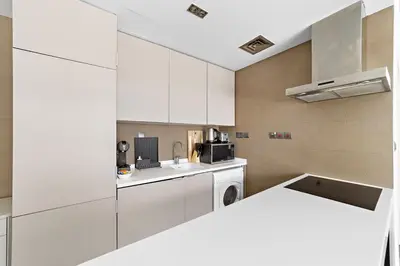 a kitchen with white cabinets and a washer at Stonetree - Brand New 1 BR in Prime Location in Dubai