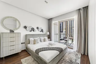 a white bedroom with a large bed and a mirror at Stonetree - Brand New 1 BR in Prime Location in Dubai