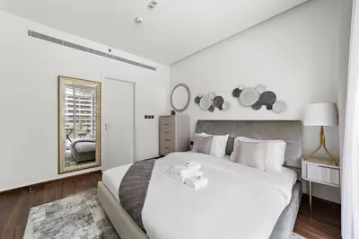 a white bedroom with a large bed and a window at Stonetree - Brand New 1 BR in Prime Location in Dubai