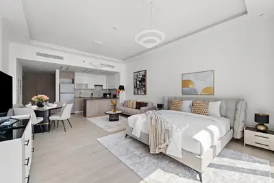 a white bedroom with a bed and a kitchen at Big Studio - WOW facilities in Dubai