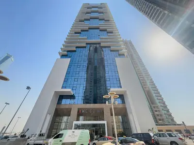 a tall building with cars parked in a parking lot at Big Studio - WOW facilities in Dubai
