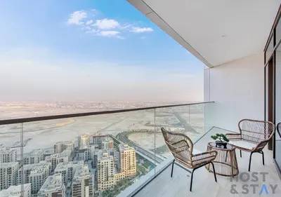 a balcony with two chairs and a view of a city at 2-BR Getaway at Palace Residences, Dubai Creek in Dubai
