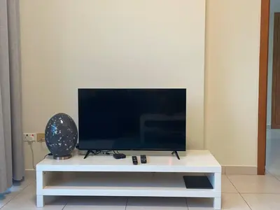 a flat screen tv sitting on a white entertainment center at Very Convenient Apartment steps to Metro and Marina Mall Managed by SunnyHomes in Dubai