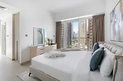 a white bedroom with a large bed and a large window at Big 1BD in JLT - Pool, Game Zone in Dubai