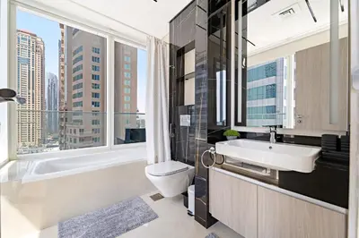 a bathroom with a sink and a toilet and a window at Big 1BD in JLT - Pool, Game Zone in Dubai