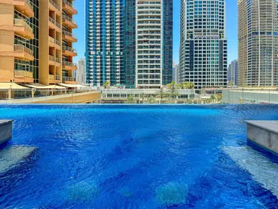 a large pool of blue water with tall buildings at Big 1BD in JLT - Pool, Game Zone in Dubai