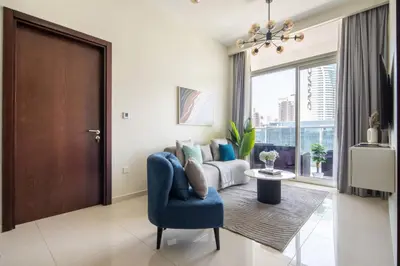 a living room with a blue chair and a window at Frank Porter - Vera Residences in Dubai