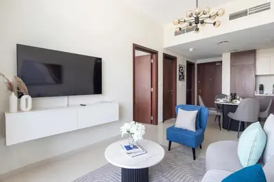 a living room with a tv and a blue chair at Frank Porter - Vera Residences in Dubai
