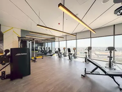 a gym with treadmills and machines in a room with windows at Stylish Studio with Great Views High Floor in Dubai