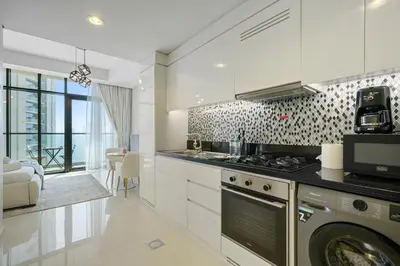 a kitchen with white cabinets and a stove top oven at Stylish Studio with Great Views High Floor in Dubai