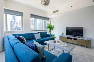 a living room with a blue couch and a tv at Frank Porter - Al Majara Tower 2 in Dubai