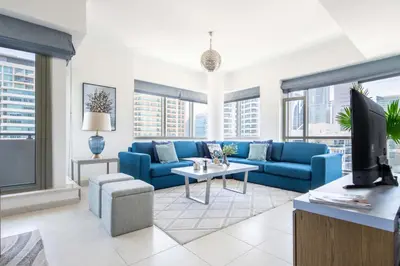 a living room with a blue couch and a tv at Frank Porter - Al Majara Tower 2 in Dubai