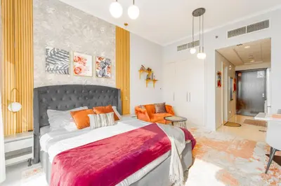 a bedroom with a large bed and an orange chair at Sleek Studio in Damac Hills - Premium Living with Top-Class Amenities, Managed by Think Realty in Dubai