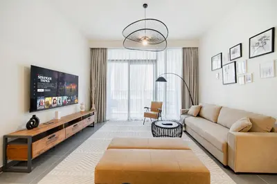 a living room with a couch and a tv at SettlerHomes - Chic Creek Edge 1BR With Harbour View in Dubai