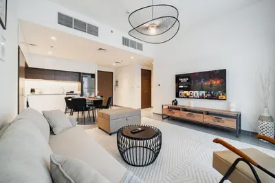 a living room with a white couch and a kitchen at SettlerHomes - Chic Creek Edge 1BR With Harbour View in Dubai