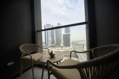 a room with chairs and a table and a window at Cosy Studio on the Binghatti Canal in Dubai