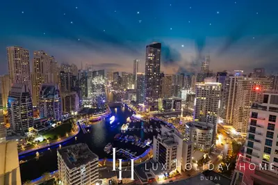 a city skyline at night with a river and buildings at LUX The Ultimate Marina View Suite in Dubai