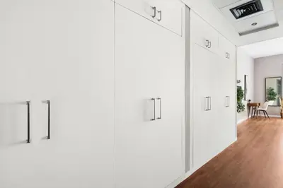 a hallway with white cabinets and a dining room at Chic studio near metro at Discovery Gardens in Dubai