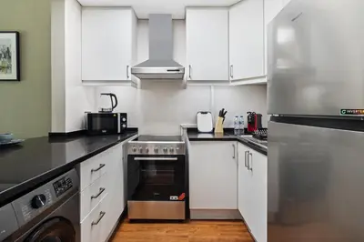 a kitchen with white cabinets and stainless steel appliances at Chic studio near metro at Discovery Gardens in Dubai