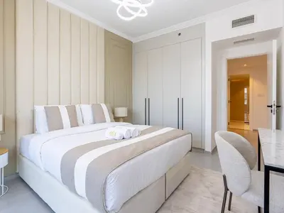 a white bedroom with a large bed and a table at 2 Bedroom Smart Home with a Panoramic Marina View in Dubai