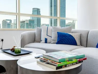 a living room with a couch and a table with books at 2 Bedroom Smart Home with a Panoramic Marina View in Dubai