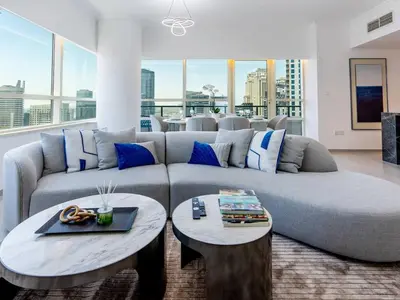 a living room with a large couch and two tables at 2 Bedroom Smart Home with a Panoramic Marina View in Dubai