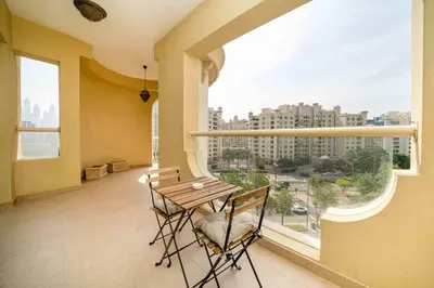 a balcony with a table and chairs and a large window at Spacious 3 Bedroom Palm Apartment in Dubai
