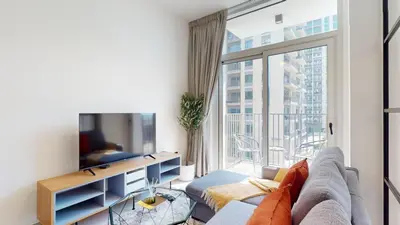 a living room with a couch and a large window at Socio Tower 2 - Neat One Bedroom in Dubai