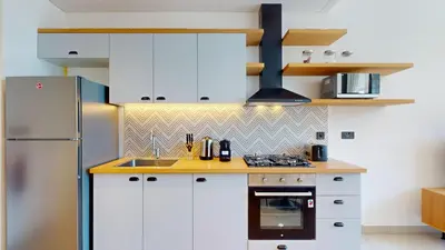 a kitchen with white cabinets and a stainless steel refrigerator at Socio Tower 2 - Neat One Bedroom in Dubai