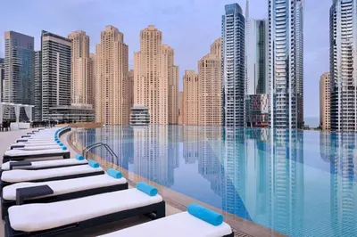 a pool with chaise lounge chairs in front of a city skyline at Vacationer l Bright 1 Bedroom l Marina & Yacht Views l Pool access & Free Wi-Fi in Dubai