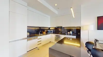a kitchen with white cabinets and black appliances at Vacationer l Bright 1 Bedroom l Marina & Yacht Views l Pool access & Free Wi-Fi in Dubai