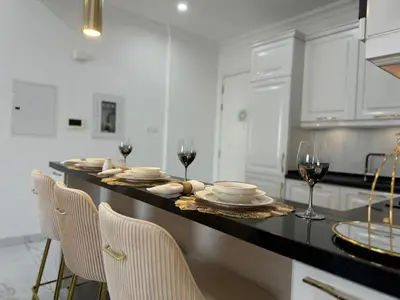 a kitchen with a table with plates and glasses of wine at ASHRI Luxurious Apartment in Arjan near Miracle Gardens in Dubai