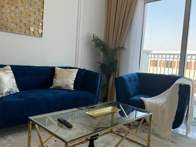 a living room with a blue couch and a glass table at ASHRI Luxurious Apartment in Arjan near Miracle Gardens in Dubai