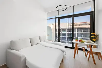 a white living room with a couch and a table at FIRST CLASS Studio Sophisticated Getaway in Dubai